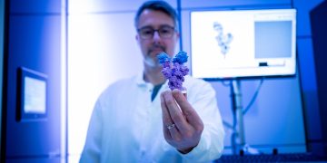 Research associate Dr. Gethin Owen holds a molecular model of the COVID-19 Omicron variant’s spike protein, which the Subramaniam lab was the first to produce using Cryo-EM