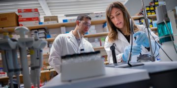 two UBC biomedical researchers in lab coats pictured in a lab